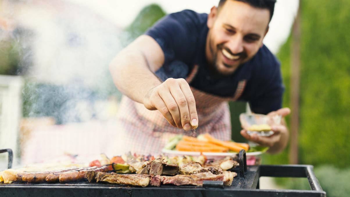 Aldi-Gasgrill: Was kann das Gerät - und welche Alternativen gibt es? Mann grillt im Garten Fleisch.