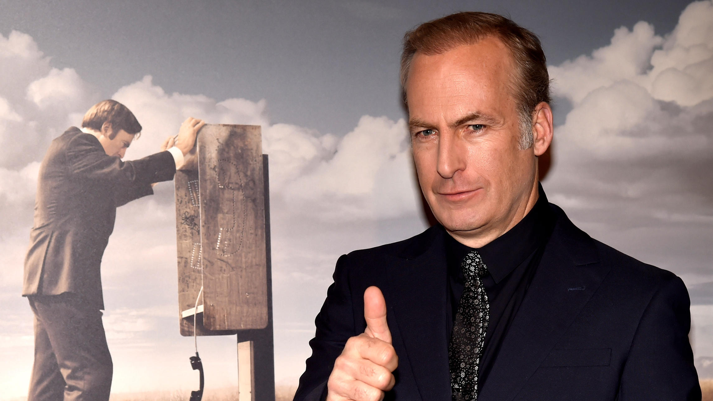 Walter White in „Breaking Bad": Was wurde aus Bryan Cranston und Co.? Bob Odenkirk vor einem „Better Call Saul"-Plakat