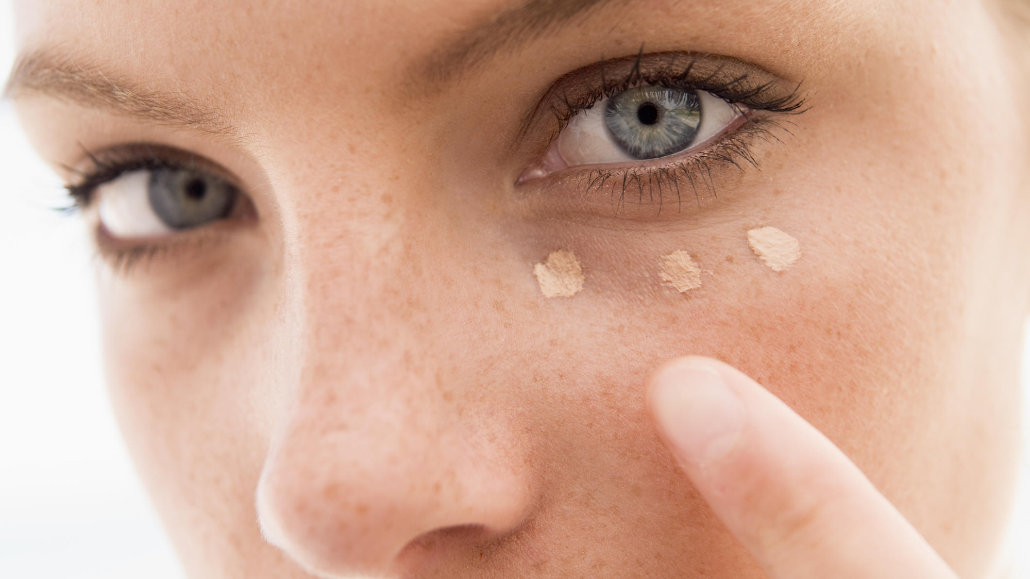 Concealer: 3 Tipps für den natürlichen Sofort-Glow Frau trägt Concealer mit drei Punkten auf.