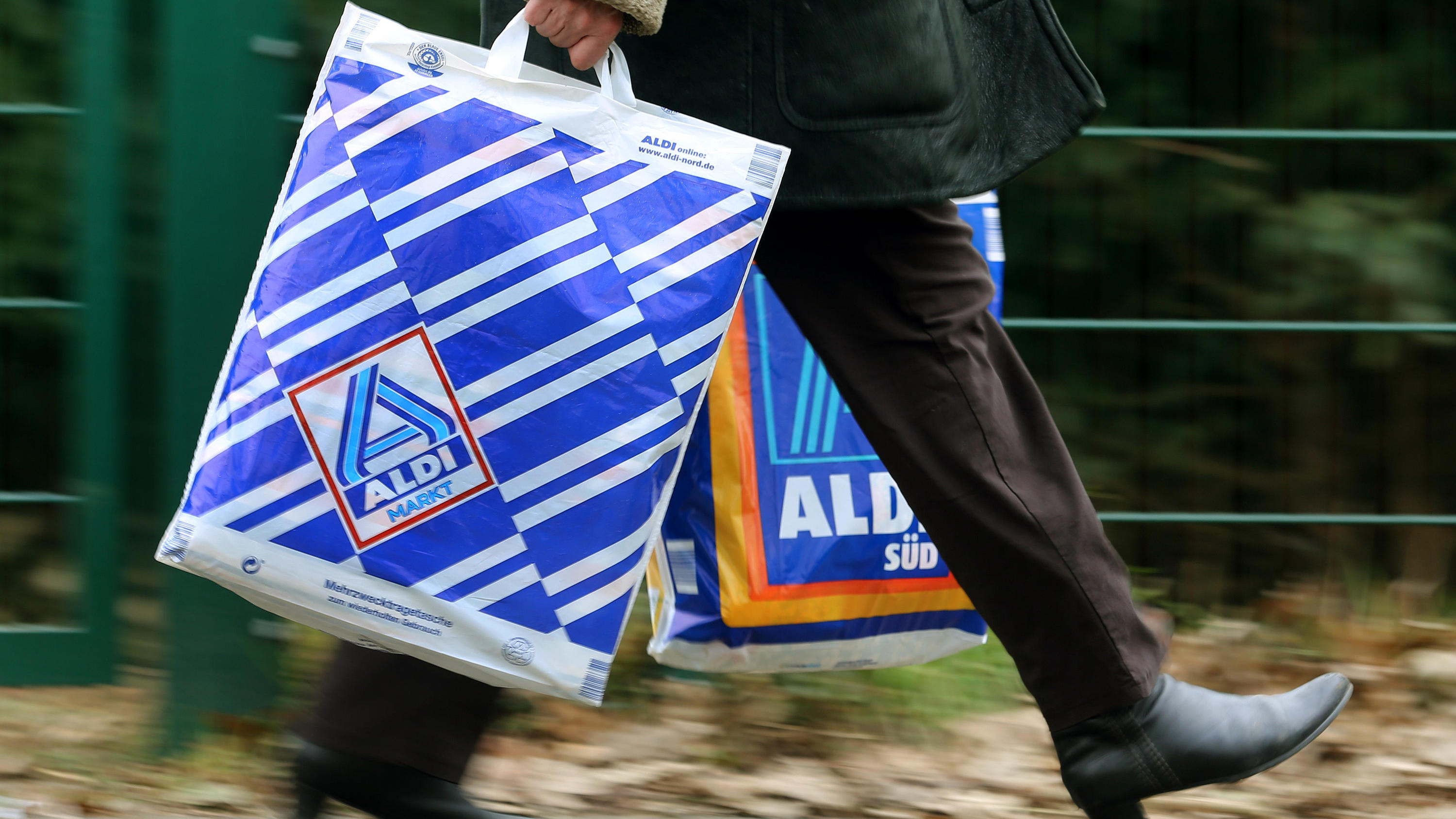 Aldi testet jetzt einen Lieferservice für Lebensmittel Die Kundin einer Aldi-Filiale trägt am 26.03.2013 in Essen (Nordrhein-Westfalen) in einer Einkaufstüte von Aldi-Nord und einer von Aldi-Süd ihre Einkäufe. Die Männer der Aldi-Erfolgsgeschichte sind die Söhne des Firmengründers Karl Albrecht: Seine Sö