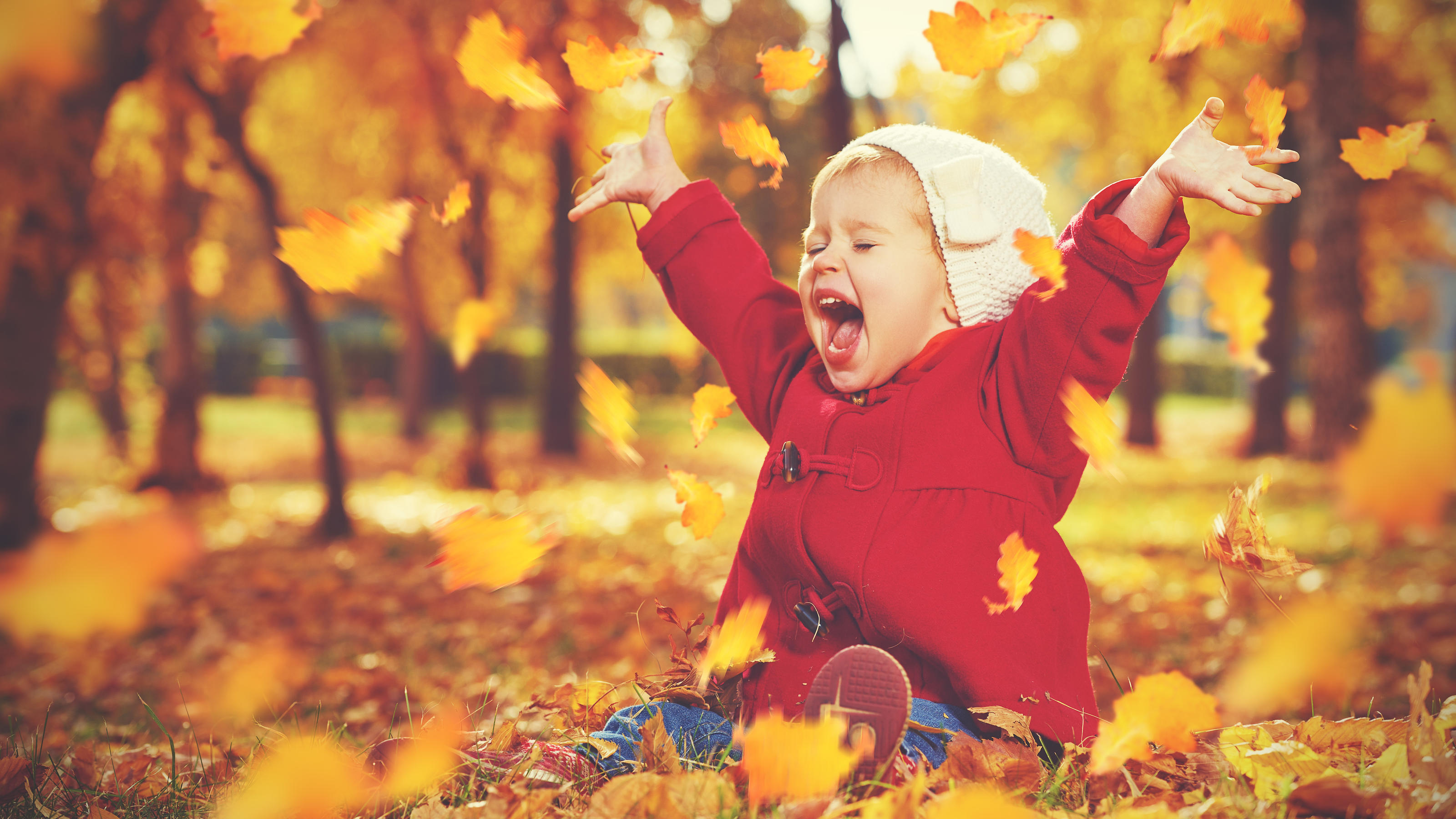 Herbst-Mode: Warum Ihre Kleine diese Outfits lieben wird Kinder-Herbstmode: Kleines Mädchen spielt mit Blättern.