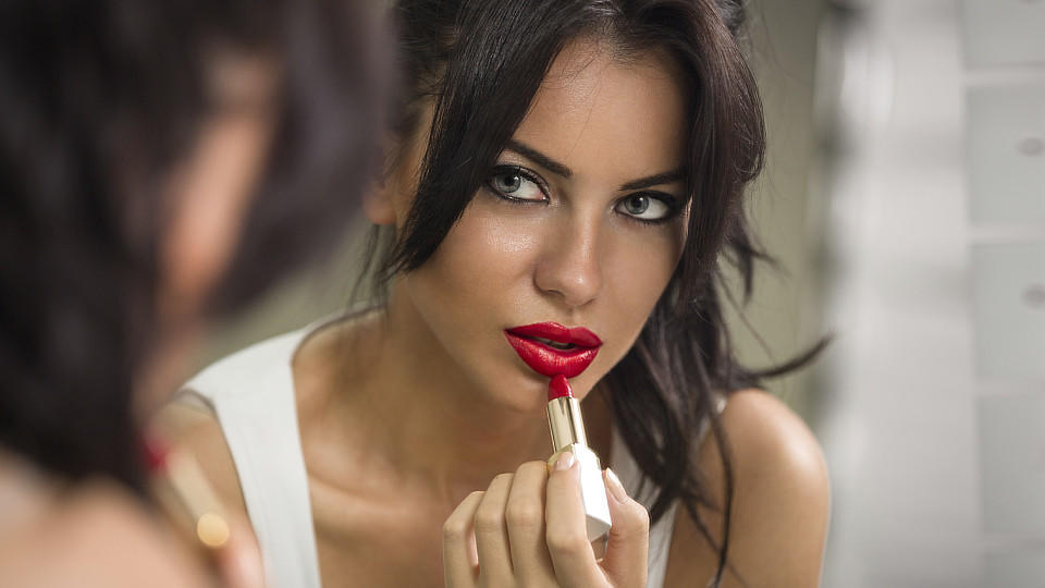 Bronzer, Selbstbräuner & Co.: 3 Tipps für sofortige Bräune Frau trägt roten Lippenstift auf
