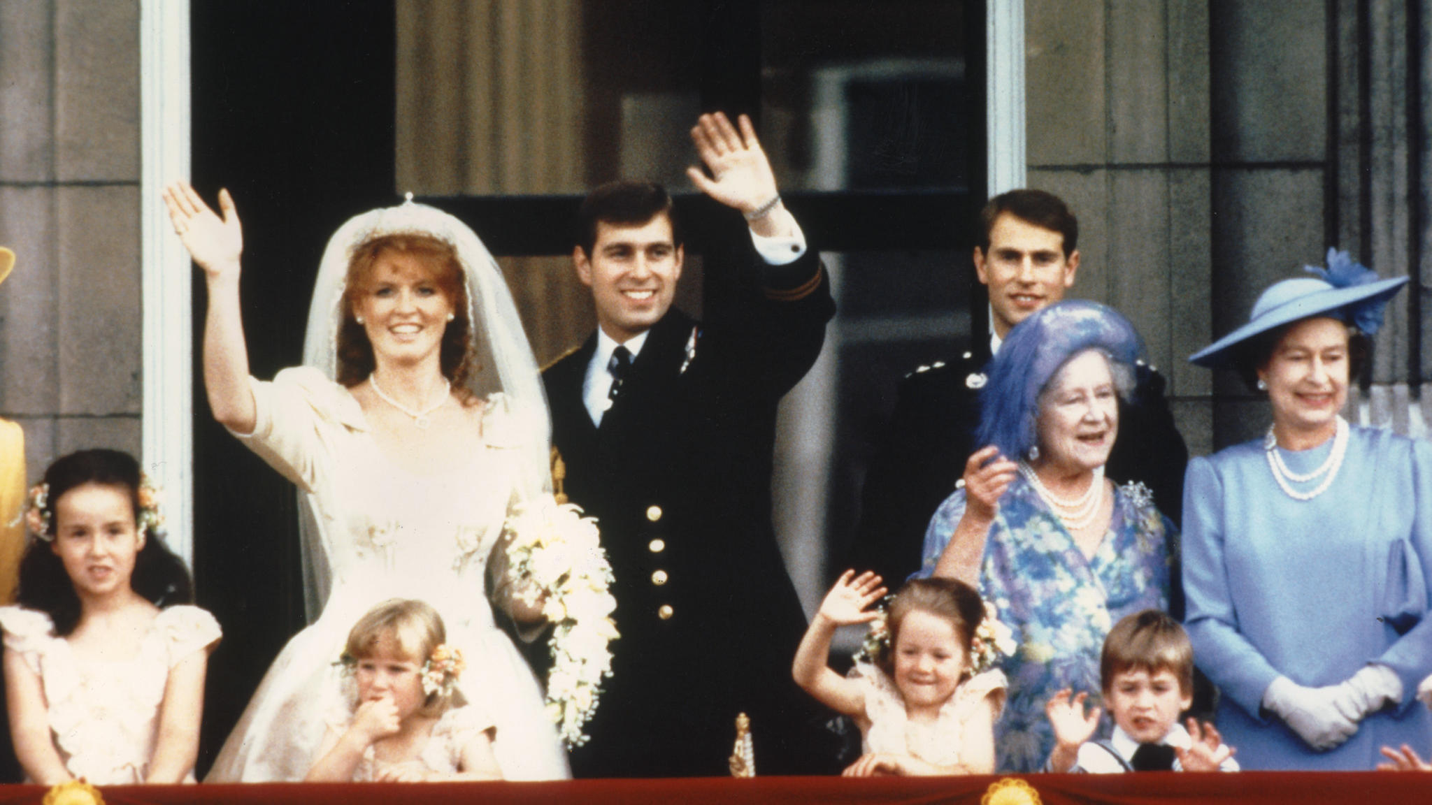 The newly wed Prince Andrew, the Duke of York and his wife Sarah Ferguson, the Duchess of York, wave to crowds 23 July 1986 from the balcony of Buckingham Palace in London while Queen Elizabeth II and Queen Mother look on. Prince Andrew desperately w