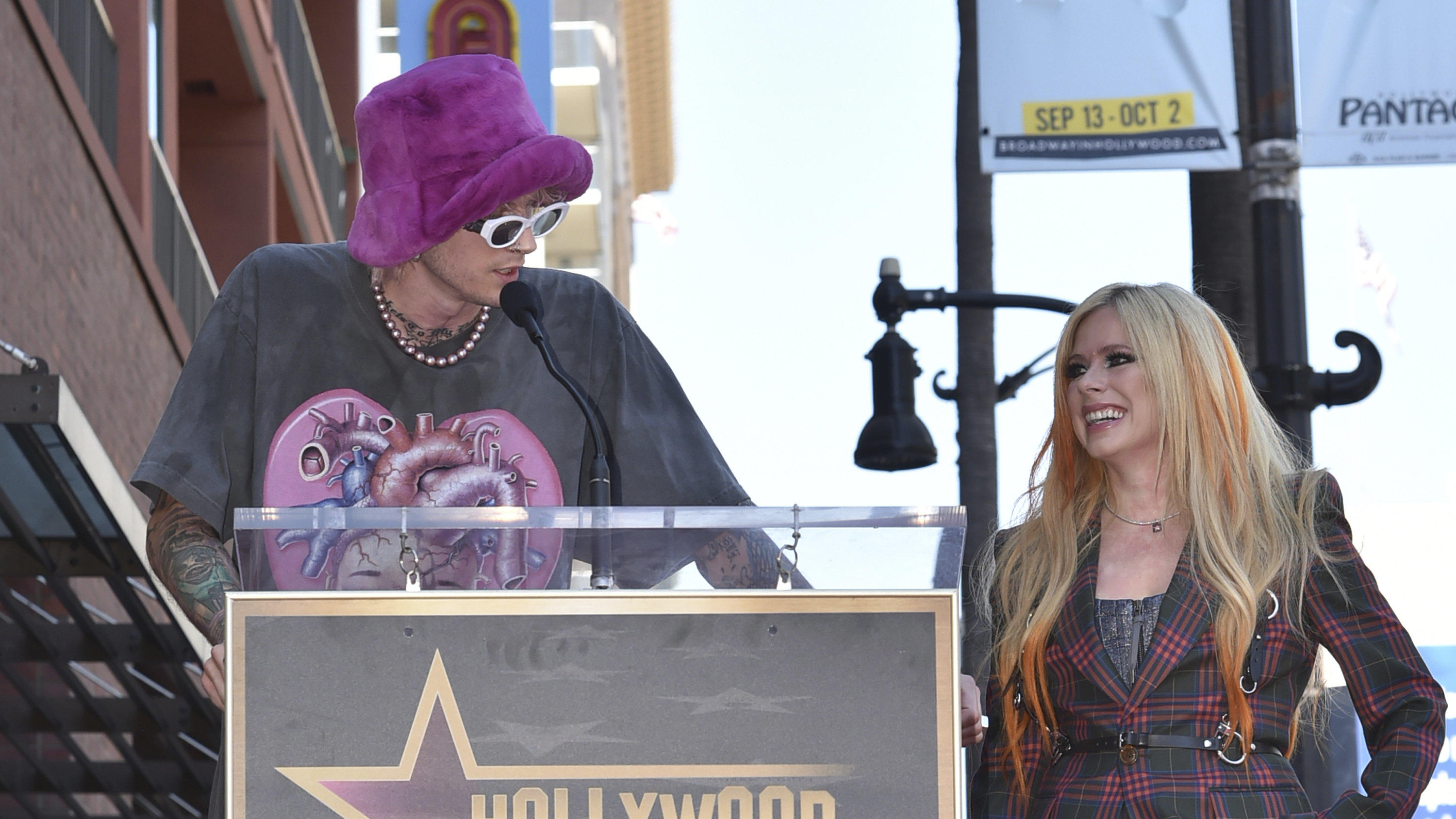 Machine Gun Kelly speaks as singer Avril Lavigne, known for her hits "Complicated" and "I'm with You," looks on during ceremony honoring Lavigne with a star on the Hollywood Walk of Fame on Wednesday, Aug. 31, 2022 in Los Angeles. (Photo by Richard S